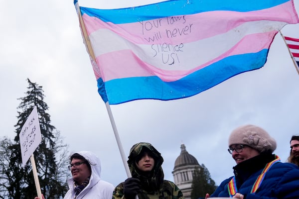 FILE - Liv Y., center, holds a transgender pride flag as people gather to protest against the Trump administration and Project 2025 near the Washington State Capitol building, Feb. 5, 2025, in Olympia, Wash. (AP Photo/Lindsey Wasson, File)