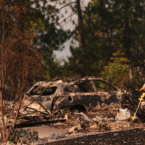 A worker with Avista moves through a property after a wildfire hit the northern part of Spokane, Wash., Monday, Aug. 3, 2026. (AP Photo/Lindsey Wasson)