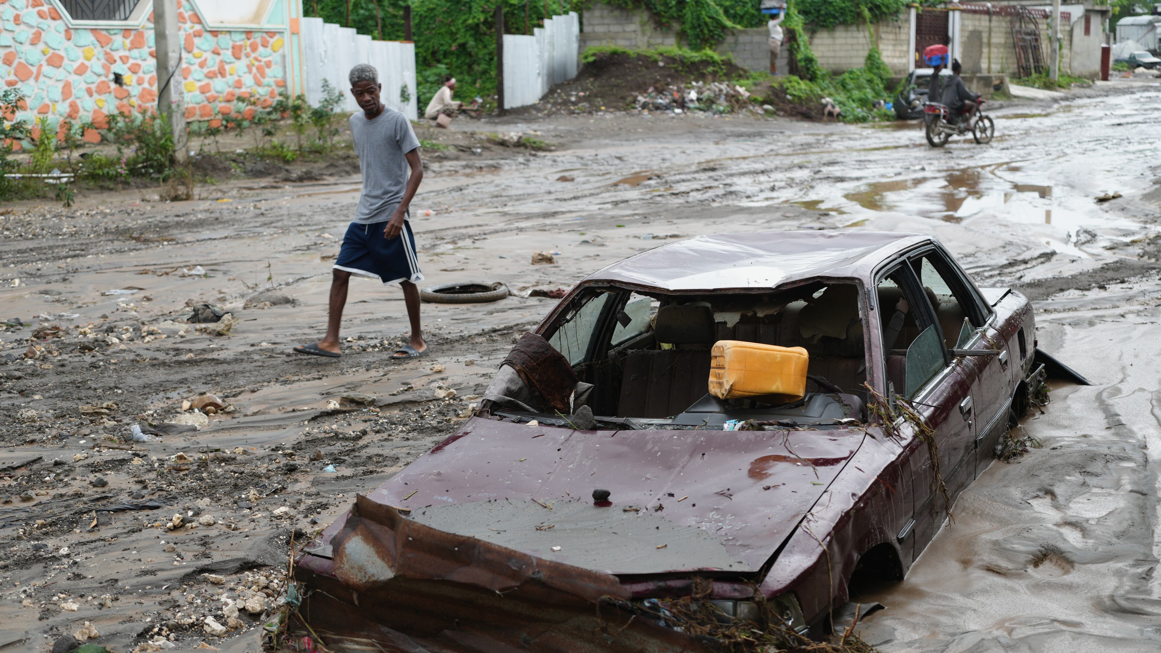 A pedestrian looks a at flooded car in the aftermath of Hurricane Melissa in Petit-Goave, Haiti, Thursday, Oct. 30, 2025. (AP Photo/Odelyn Joseph),