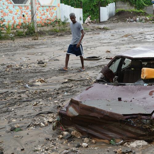 A pedestrian looks a at flooded car in the aftermath of Hurricane Melissa in Petit-Goave, Haiti, Thursday, Oct. 30, 2025. (AP Photo/Odelyn Joseph),