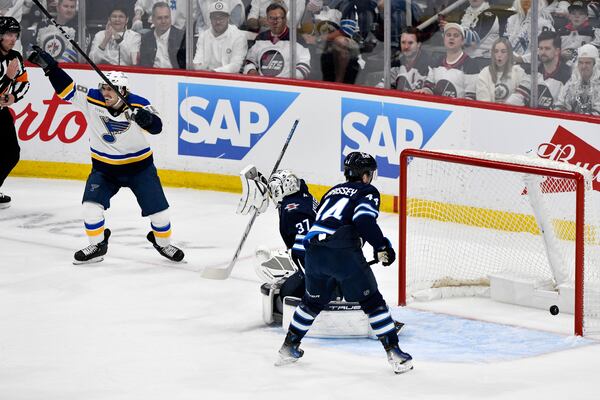 St. Louis Blues' Robert Thomas (18) celebrates a goal on on Winnipeg Jets goaltender Connor Hellebuyck (37) on a shot by Jimmy Snuggerud, not shown, during the first period of an NHL playoff game in Winnipeg, Monday April 21, 2025. (Fred Greenslade/The Canadian Press via AP)