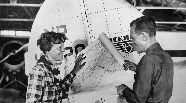 In this undated photo, aviator Amelia Earhart, left, and navigator Fred Noonan pose with a map of the Pacific Ocean showing the planned route of their round-the-world flight. Contributed by AP Photo