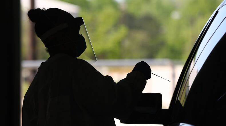 In this file photo, Emory Hospital registered nurse Aisha Bennett takes a nasal swab test for COVID-19 in a drive through site at the Georgia International Horse Park.(CURTIS COMPTON/CURTIS.COMPTON@AJC.COM)