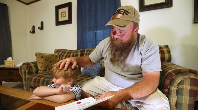 U.S. Army veteran Bobby Fisk helps his 5-year-old son Oi with his math homework. Fisk, who suffered injuries from two IED explosions in Afghanistan, has had multiple problems getting health care at the VA. Curtis Compton/ccompton@ajc.com