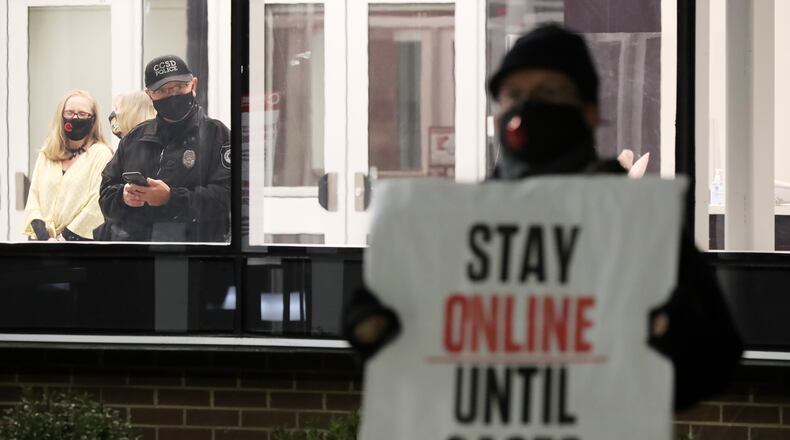 012121 Marietta: A CCSD police officer keeps an eye from inside the building on hundreds of Cobb County teachers and staff holding a protest in the parking lot during the school board meeting at the Cobb County School District's Offices on Thursday, Jan. 21, 2021, in Marietta. Cobb teachers are pressing the district for improved COVID-19 response. Curtis Compton / Curtis.Compton@ajc.com”