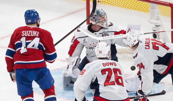 Montreal Canadiens' Nick Suzuki (14) scores against Washington Capitals goaltender Logan Thompson, center top, during the second period of Game 3 of a first-round NHL hockey playoff series in Montreal, Friday, April 25, 2025. (Christinne Muschi/The Canadian Press via AP)