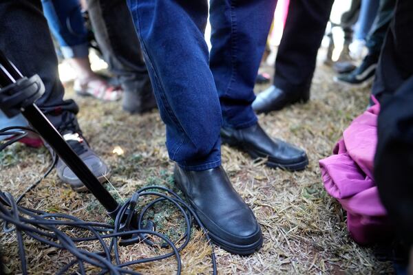 The feet of Brazil's former President Jair Bolsonaro are photographed as he stops to speak with the press while leaving the Secretariat of Penitentiary Administration after the Supreme Court ordered him to be fitted with an electronic ankle monitor in Brasilia, Brazil, Friday, July 18, 2025. (AP Photo/Eraldo Peres)