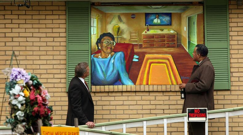 Buckhead businessman John Gordon, left, and the Rev. Anthony Motley of Lindsay Street Baptist Church, look at a Janssen Robinson mural of Kathryn Johnson painted on plywood over her boarded-up home in the English Avenue community in November 2008. The two men are working to improve the quality of life in the community following the police shooting of the 92-year-old Johnston. CURTIS COMPTON / AJC file