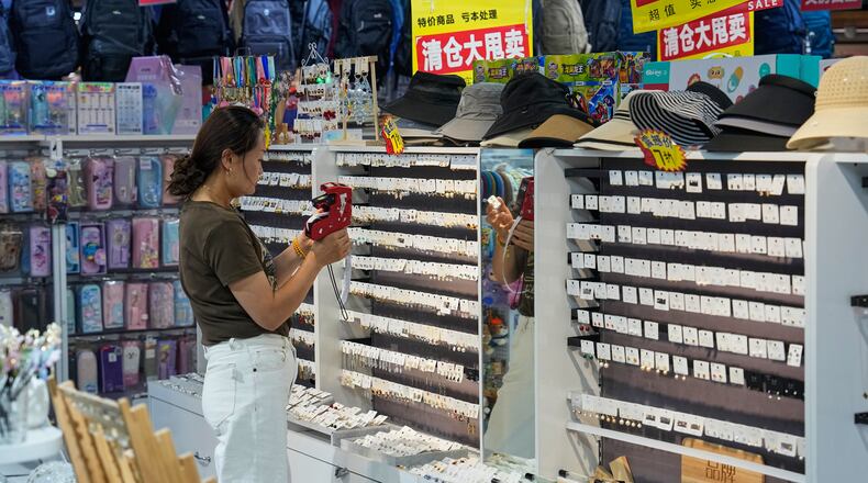 A vendor puts price tag on the ear rings for sale at her store in Beijing, China on Wednesday, July 15, 2026. (AP Photo/Andy Wong)