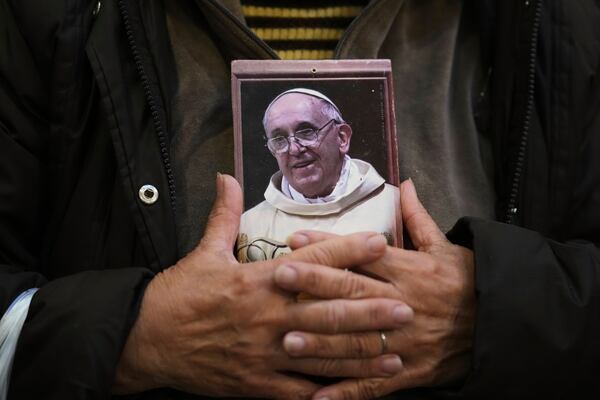 A faithful holds a portrait of late Pope Francis at the Basílica de San José de Flores, where he worshipped as a youth, following the Vatican's announcement of his death in Buenos Aires, Argentina, Monday, April 21, 2025. (AP Photo/Gustavo Garello)