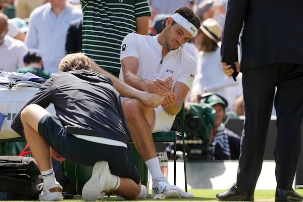 Taylor Fritz of the U.S. gets medical assistance during the men's singles quarter final match against Karen Khachanov of Russia at the Wimbledon Tennis Championships in London, Tuesday, July 8, 2025.(AP Photo/Kin Cheung)