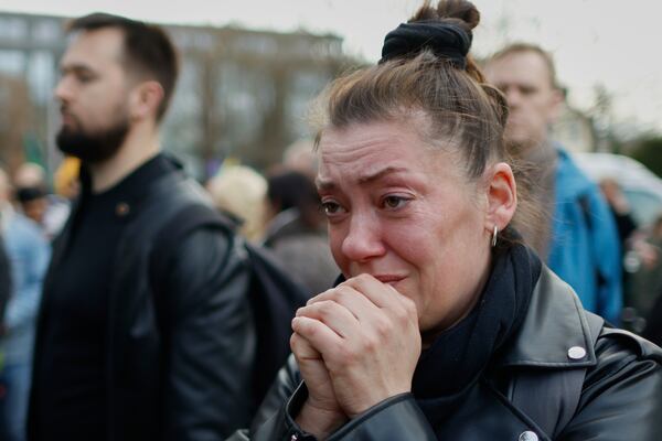 A woman reacts as she and other people come to pay their last respects in memory of three U.S. Army soldiers found dead on Monday at a training range in Pabrade, near the U.S. Embassy in Vilnius, Lithuania, Tuesday, April 1, 2025. (AP Photo/Mindaugas Kulbis)
