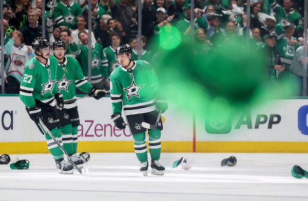 A cowboy hat is thrown onto the ice as Dallas Stars' Mason Marchment (27) and Miro Heiskanen, center, celebrate with Mikael Granlund, right, after Granlund earned a hat trick in the third period of Game 4 of a second-round NHL hockey playoff series in Dallas, Tuesday, May 13, 2025. (AP Photo/Gareth Patterson)