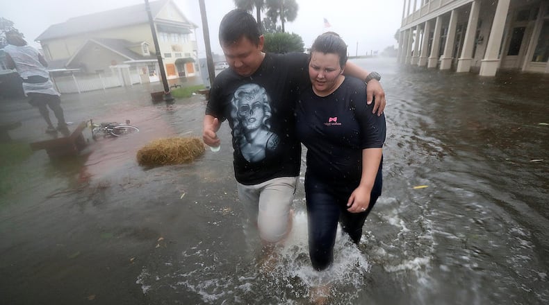 St. Marys residents Michael and Tori Munton make their way through their city's flooded streets as the storm surge from Hurricane Matthew hit on Friday. Curtis Compton /ccompton@ajc.com