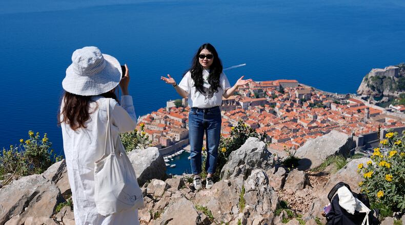 Tourists take photos of themselves on a hill overlooking the old town of Dubrovnik, Croatia, Monday, April 27, 2026. (AP Photo/Darko Bandic)