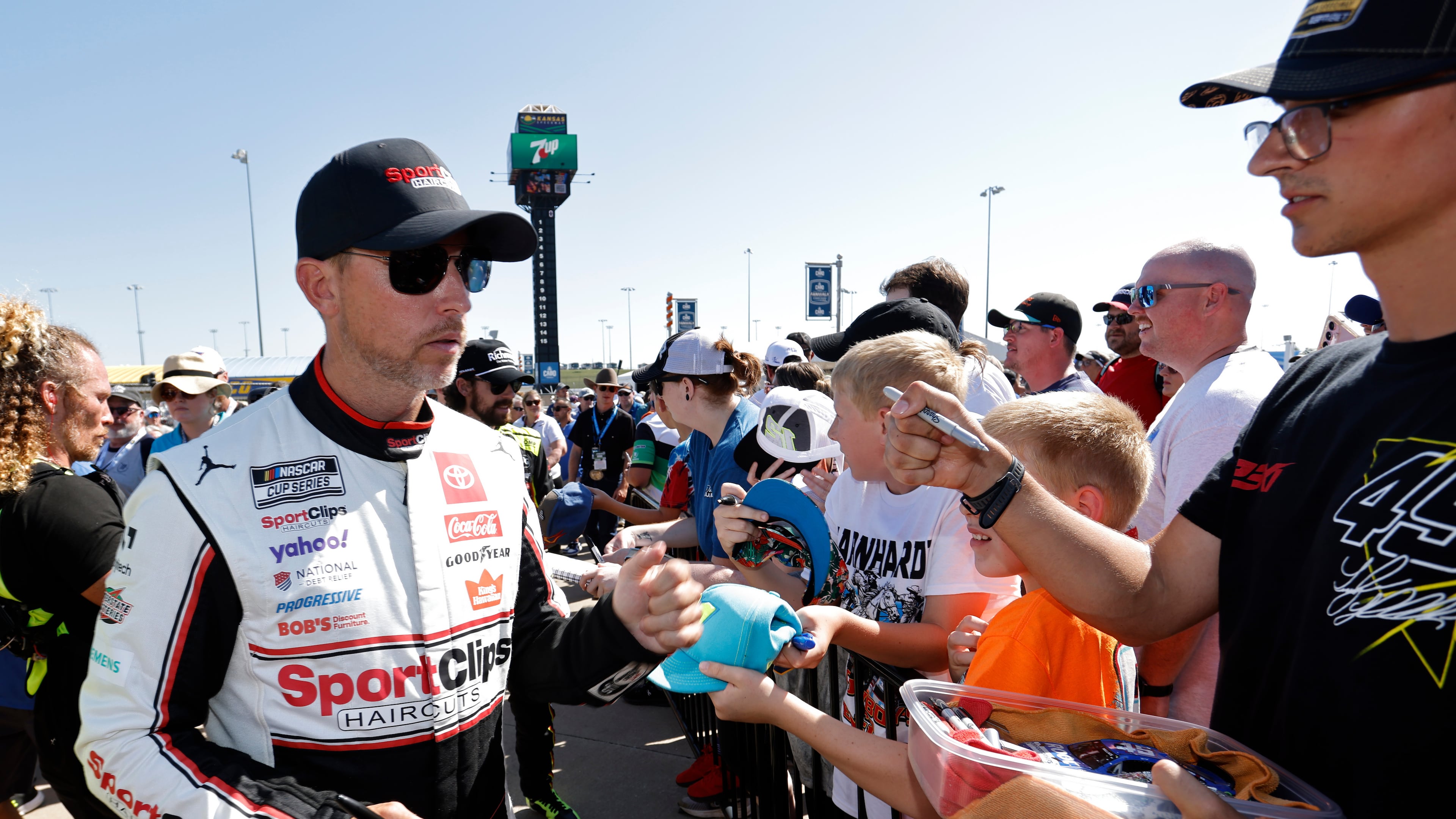 Denny Hamlin, left, gives autographs before a NASCAR Cup Series auto race at Kansas Speedway in Kansas City, Kan., Sunday, Sept. 28, 2025. (AP Photo/Colin E. Braley)