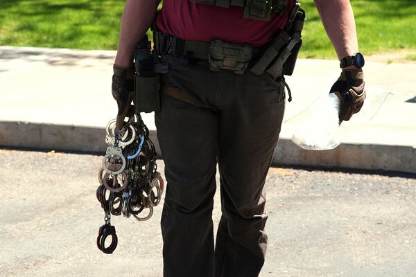 FILE - A federal agent holds handcuffs outside immigration court, May 21, 2025, in Phoenix. (AP Photo/Ross D. Franklin, File)
