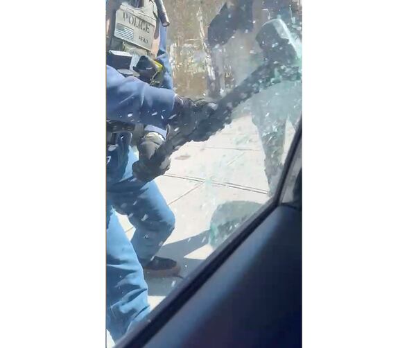In this image from video provided by Marilu Domingo Ortiz, an ICE agent uses a hammer to smash the window of a car to arrest a man who they claim was in the process of applying for asylum, in New Bedford, Mass., Monday, April 14, 2025. (Marilu Domingo Ortiz via AP)
