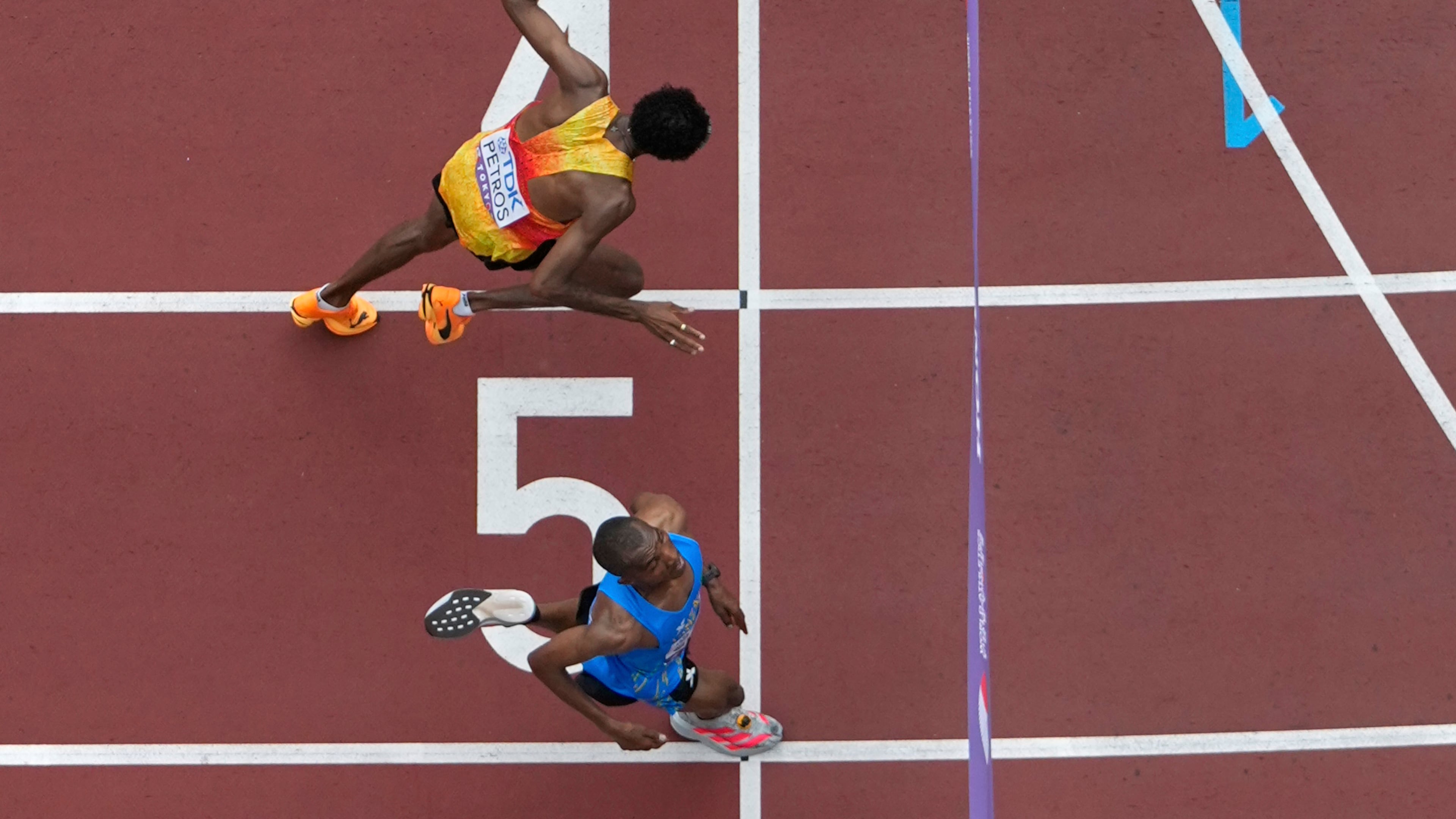 Tanzania's Alphonce Felix Simbu, bottom, crosses the finish line ahead of Germany's Amanal Petros to win the men's marathon at the World Athletics Championships in Tokyo, Monday, Sept. 15, 2025. (AP Photo/Bernat Armangue)