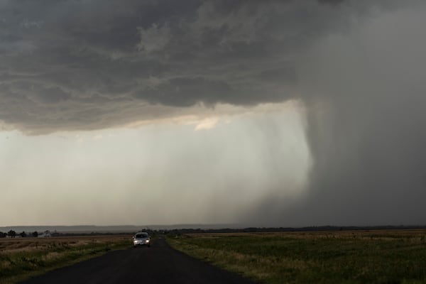 A car moves away from an approaching storm with a rain shaft during a Project ICECHIP operation on Tuesday, June 3, 2025, near Tipton, Okla. (AP Photo/Carolyn Kaster)