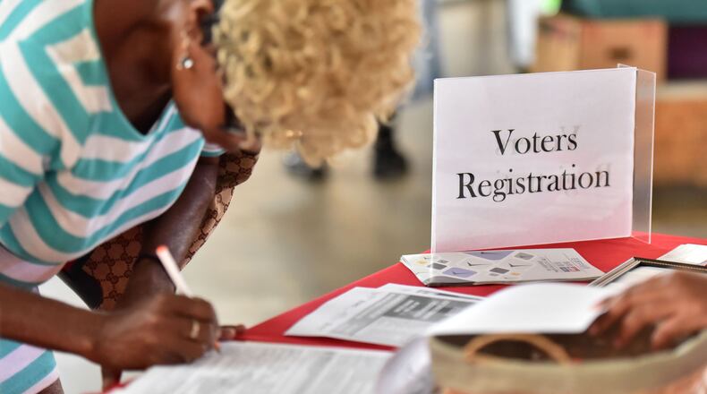 Sharon Huff, of Atlanta, fills in voter registration form while at the Sweet Auburn Curb Market in this file photo from August. Hyosub Shin, hshin@ajc.com