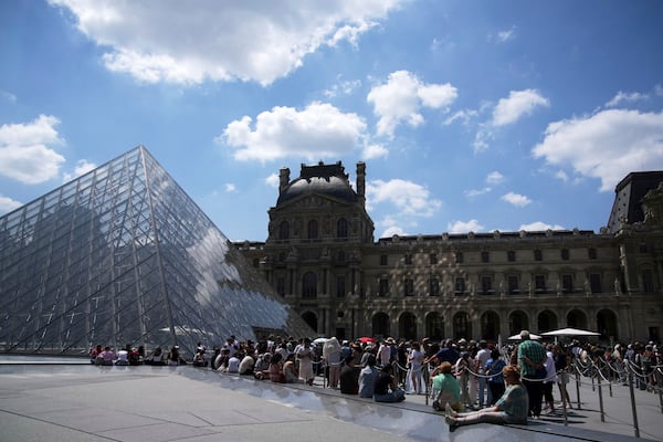 Tourists wait in line outside the Louvre museum which failed to open on time Monday, June 16, 2025 in Paris. (AP Photo/Christophe Ena)