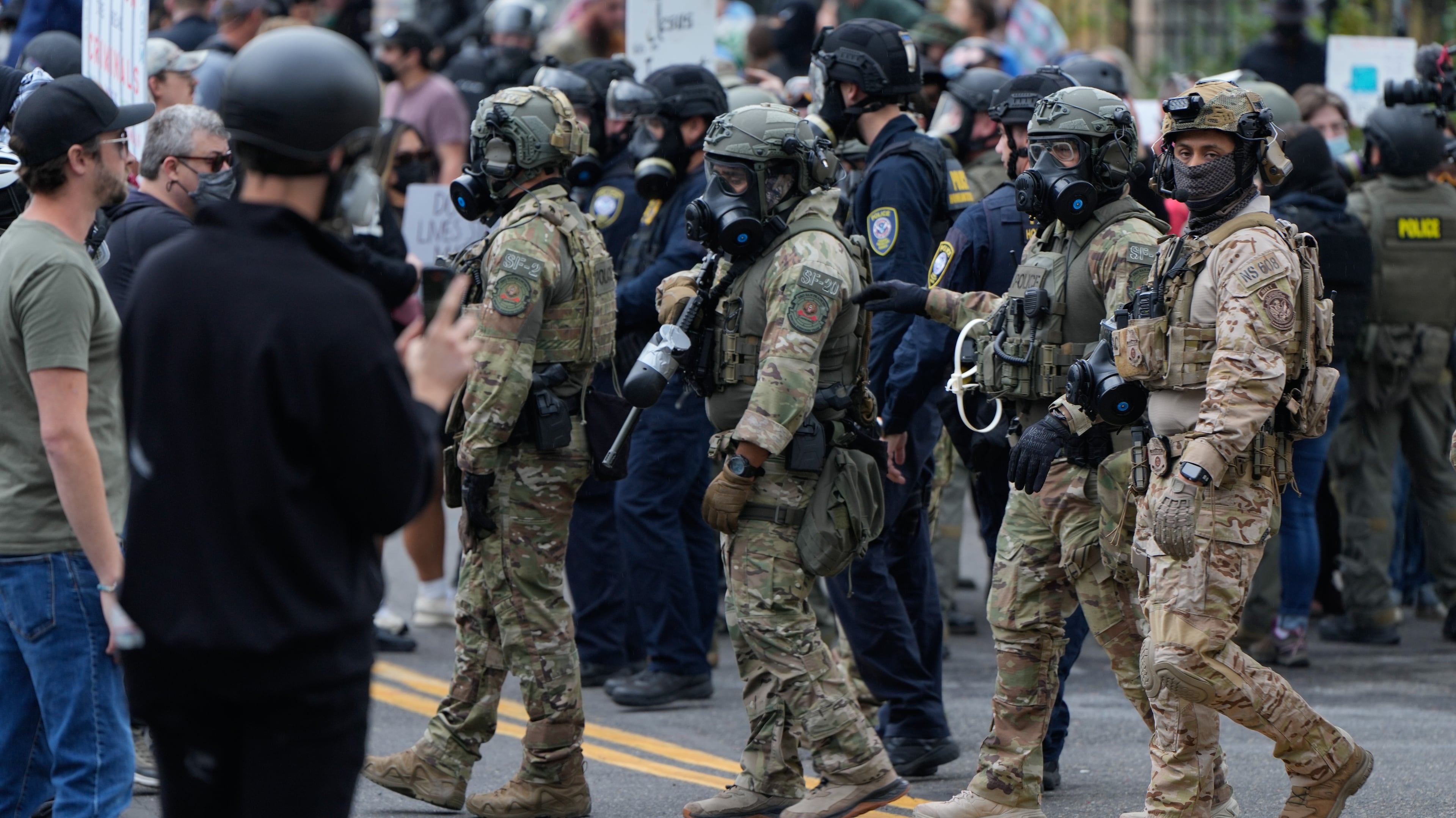 Law enforcement officers move towards protesters to make a path for a vehicle to leave a U.S. Immigration and Customs Enforcement facility on Saturday, Oct. 4, 2025, in Portland, Ore. (AP Photo/Jenny Kane)