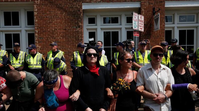 Members of the Charlottesville community and protest groups locked arms in front of police on Aug. 12. The next day, the organizer of a Unite the Right rally was punched by a man when he attempted to make a speech.