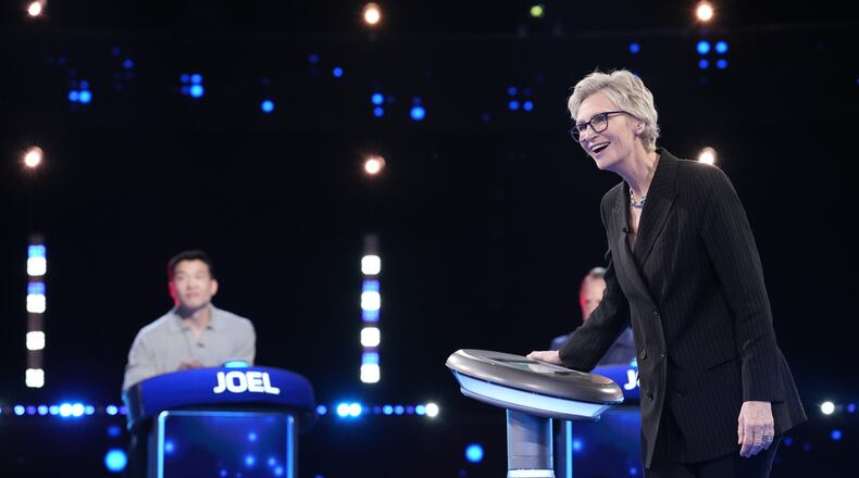 Jane Lynch (right) hosts as Joel Kim Booster competes on Fox’s “Celebrity Weakest Link.” The trivia game show is the latest in an array of primetime game shows coming to metro Atlanta. (Greg Gayne/Fox 2025)