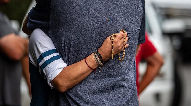 Two people hug Saturday morning outside a Forsyth County home where two children, aged 9 and 12, were killed in an overnight fire.