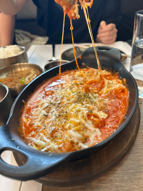 A cast iron dish of rose tteokbokki with melted cheese