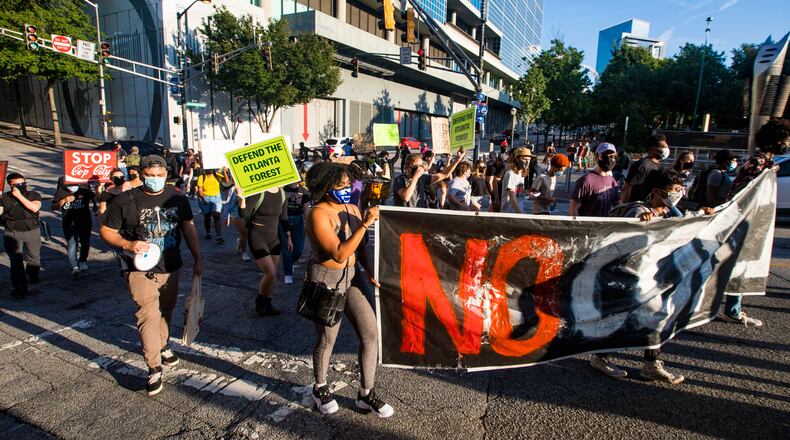 Protestors march through downtown Atlanta to the World of Coca-Cola on Friday, Sept 3, 2021 to demonstrate against the proposed police training facility to be voted on next week.  Coke is one of several corporations in Atlanta supporting the proposed 85-acre police training facility for police and firefighters to be built in unincorporated DeKalb County.  (Jenni Girtman for The Atlanta Journal-Constitution)