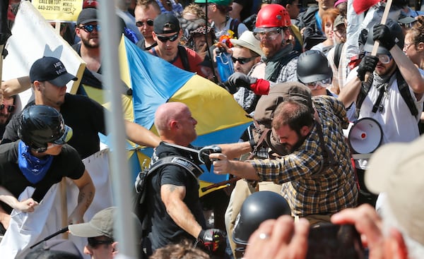 White nationalist demonstrators clash with counter demonstrators at the entrance to Lee Park in Charlottesville, Va., Saturday, Aug. 12, 2017. Gov. Terry McAuliffe declared a state of emergency and police dressed in riot gear ordered people to disperse after chaotic violent clashes between white nationalists and counter protestors. (AP Photo/Steve Helber)