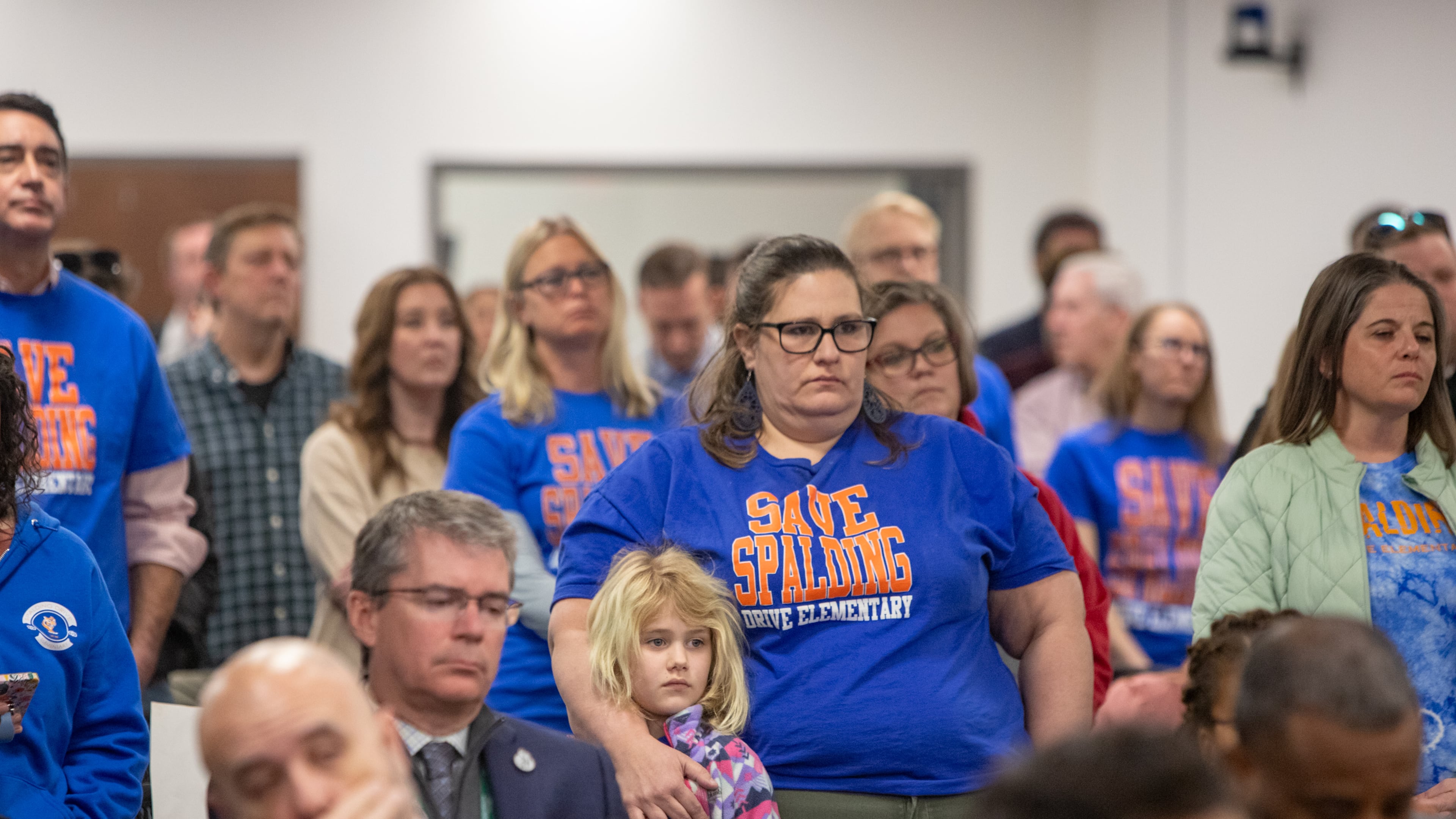 Spalding Drive Elementary 2nd Grader Ada Shupe, center, is with her mother Alona Shupe as they prepare for the vote at the Fulton County Board of Education meeting Thursday, Feb 20, 2025.  Parents, teachers, students and community members filled the public comment time asking to keep the East Point and Sandy Springs schools open.   The board votes to close both Spalding Drive Elementary and Parklane Elementary. (Jenni Girtman for The Atlanta Journal-Constitution)