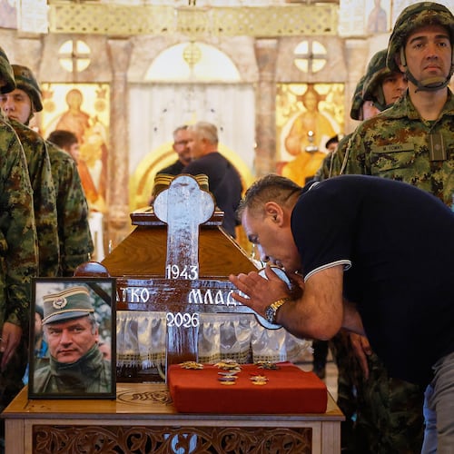 A man touches the cross as Serbian national military servicemen stand around the coffin of the former Bosnian Serb army commander Ratko Mladic, who died last week while serving a life sentence for genocide and other atrocities during the war in Bosnia, at the St. Luka Church, in Belgrade, Serbia, Monday, Sept. 7, 2026. (AP Photo/Marko Drobnjakovic)