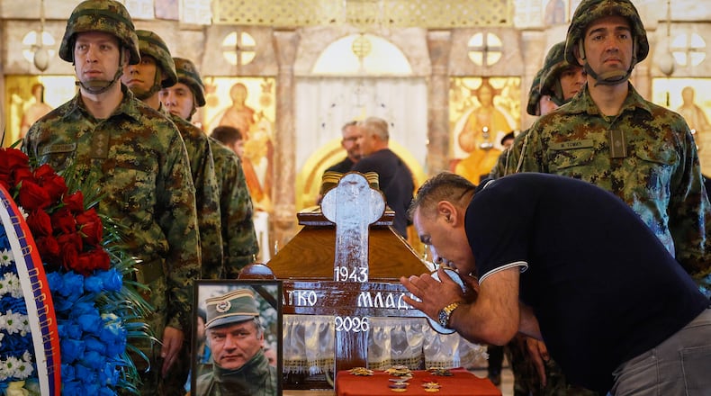 A man touches the cross as Serbian national military servicemen stand around the coffin of the former Bosnian Serb army commander Ratko Mladic, who died last week while serving a life sentence for genocide and other atrocities during the war in Bosnia, at the St. Luka Church, in Belgrade, Serbia, Monday, Sept. 7, 2026. (AP Photo/Marko Drobnjakovic)