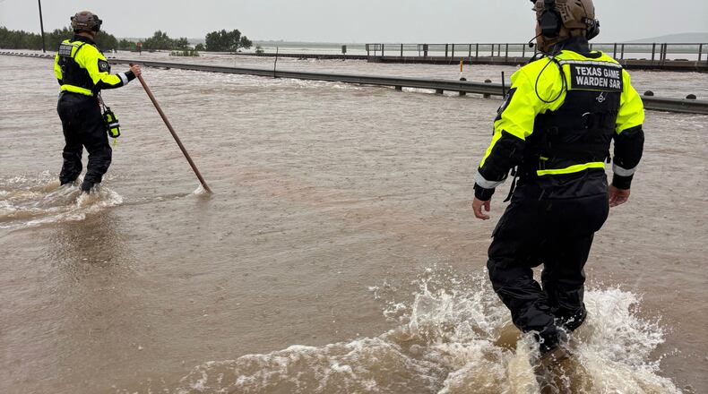 In this handout photo provided by the Texas Parks and Wildlife Department, game wardens walk through high waters from heavy rains in Uvalde County, Texas, on Tuesday, July 14, 2026. (Texas Parks and Wildlife Department via AP)