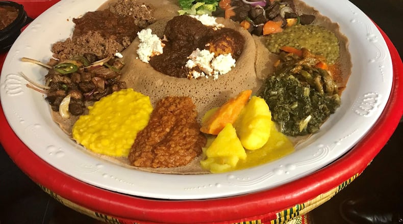 The Ghion Cultural Platter is a good way to sample a variety of Ethiopian dishes at Ghion Cultural Hall. The platter includes multiple lentil dishes, cooked vegetables, dry tibs (sauteed lamb or beef cubes), awaze tibs (tibs seasoned with a spicy sauce made from a blend of berbere, paprika and other spices), and doro wot (stewed chicken), all set atop spongy injera bread. The injera bread is used instead of utensils for scooping up the food. LIGAYA FIGUERAS / LFIGUERAS@AJC.COM