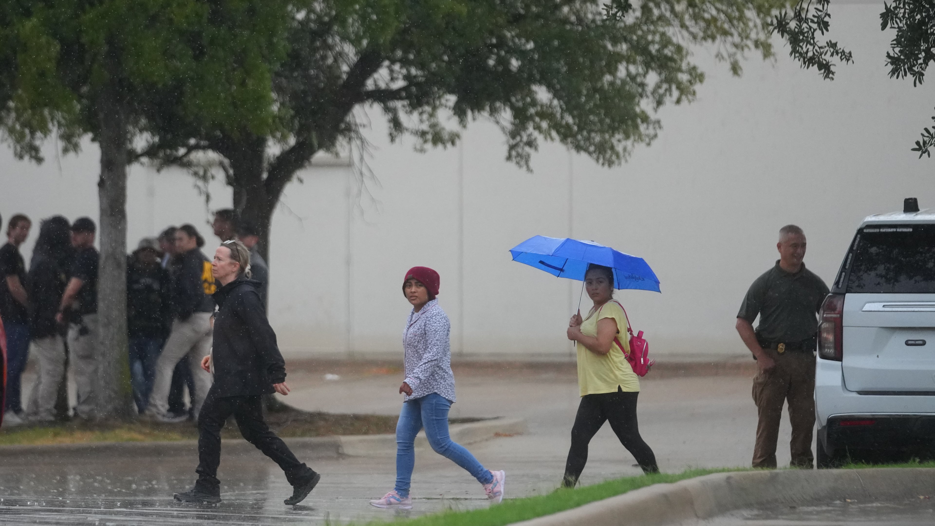 People gather with police at a staging area near a U.S. Immigration and Customs Enforcement office after a reported shooting, in Dallas on Wednesday, Sept. 24, 2025. (AP Photo/Julio Cortez)