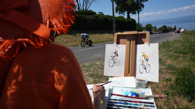 A woman draws as Britain's Fred Wright rides during the sixteenth stage of the Tour de France cycling race, an indivdual time-trial with start in Evian-Les-Bains and finish in Thonon-les-Bains, France, Tuesday, July 21, 2026. (AP Photo/Thibault Camus)