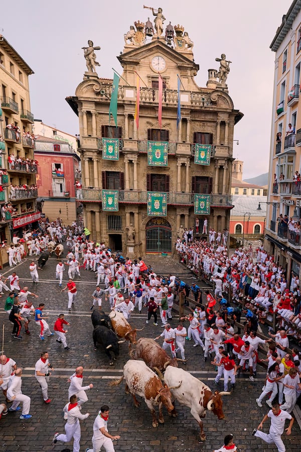 Revelers run with bulls from Fuente Ymbro ranch during the first day of the running of the bulls at the San Fermín fiestas in Pamplona, Spain, Monday, July 7, 2025. (AP Photo/Miguel Oses)