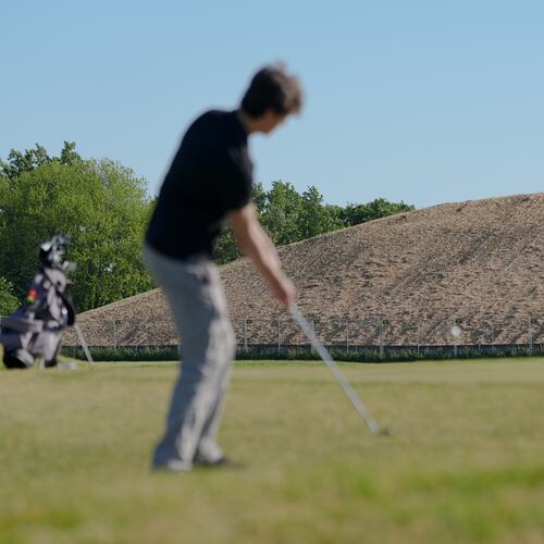 A pile of debris is seen in the background as Roman Sandoli, right, prepares to putt at the East Potomac Golf Course, Sunday, May 3, 2026, in Washington. (AP Photo/Julia Demaree Nikhinson)