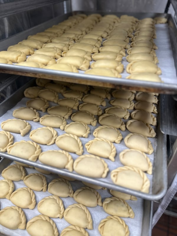 Three metal trays filled with pierogi all folded with an intricate braid pattern.