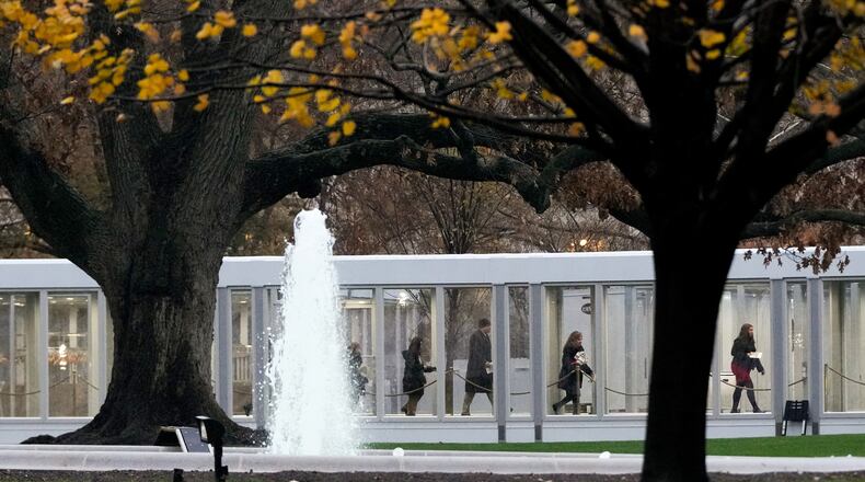 People walk through a newly constructed covered walkway on the North Lawn while arriving for a White House tour, Tuesday, Dec. 2, 2025, in Washington, as tours resume for the first time since construction of a new ballroom began at the White House. (AP Photo/Julia Demaree Nikhinson)