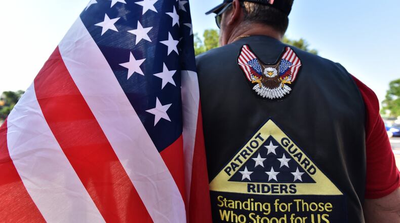 A Patriot Guard Rider holds an American flag as the group sets up a “flag line” before the May 18 funeral service for Kelvin Ansari, a 10-year veteran of the Savannah Police Department and an Army veteran, who was killed on the job. The guard has expanded its mission to include offering tribute to firefighters, police officers and other public safety personnel. HYOSUB SHIN / HSHIN@AJC.COM
