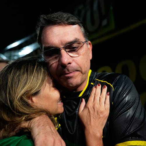 Flavio Bolsonaro, son of ex-President Jair Bolsonaro, hugs a supporter during a vigil outside the former president's residence in Brasília, Brazil, Saturday, Nov. 22, 2025, after his father's arrest earlier in the day, carried out days before he was set to start serving his 27-year sentence for leading a coup attempt. (AP Photo/Eraldo Peres)