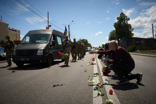 Villagers throw flowers on the road during the funeral procession of Maksym Baluyev, a soldier who was killed in battle with the Russian troops, in the village of Novi Petrivtsi close to Kyiv, Ukraine, Monday, June 23, 2025. (AP Photo/Efrem Lukatsky)