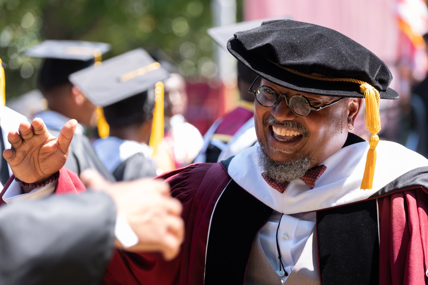 Illya Davis, director of freshmen and seniors' academic success at Morehouse College, greets students as they head to the stage to receive their diplomas Sunday, May 17, 2026. (Ben Gray for the AJC)