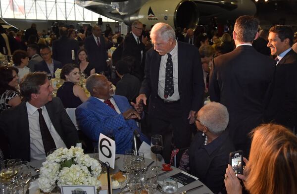 Ted Turner (standing) and Hank Aaron talk as Billye Aaron (right) looks on during the second annual Bill Foege Global Health Awards on May 9, 2018, at the Delta Flight Museum in Atlanta. 