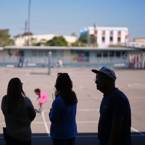 Teachers look on as students play on the playground at Perkins K-8 School Thursday, Nov. 13, 2025, in San Diego. (AP Photo/Gregory Bull)